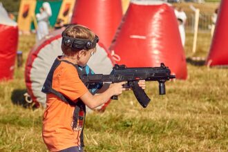 Юный игрок целится из футуристичного бластера LASERWAR.