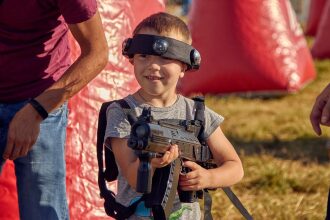 Мальчик в шлеме LASERWAR с автоматом готовится к игре.