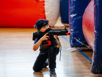 Мальчик в тактическом обмундировании LASERWAR целится из оружия.