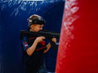 Мальчик в шлеме LASERWAR с автоматом наготове.
