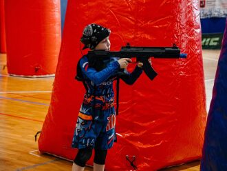Юный боец LASERWAR целится из оружия в красном укрытии.