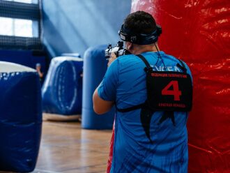 Боец «Красной команды» LASERWAR целится из оружия.