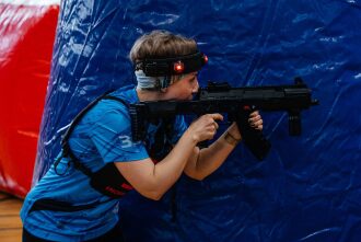 Девушка в синей форме LASERWAR прицеливается из оружия.