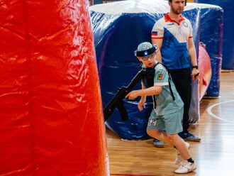 Мальчик в бирюзовой форме LASERWAR бежит с оружием.
