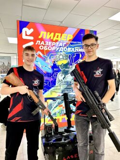 Два парня с лазертаг-оружием у баннера LASERWAR.