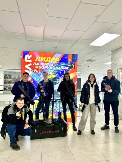 Группа игроков LASERWAR позирует с оружием у баннера