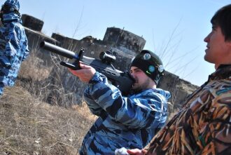 Боец LASERWAR прицеливается из футуристичного оружия.