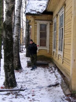Лазертаг-боец у старого дома в снегу.