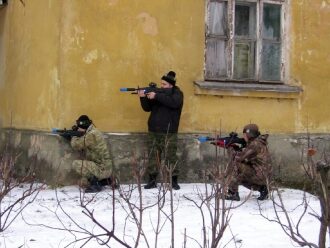 Лазертаг-бойцы у старого здания в зимнем антураже.