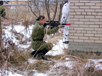 Снайпер LASERWAR в зимнем укрытии у кирпичной стены.