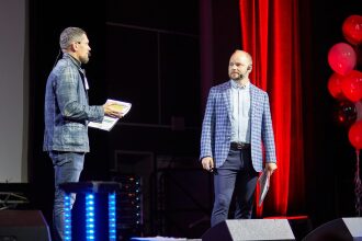 Два спикера обсуждают детали презентации на сцене.