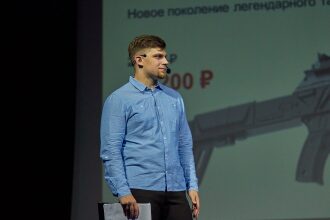 Мужчина в голубой рубашке на фоне презентации LASERWAR.