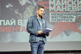 Ведущий мероприятия держит планшет с документами.