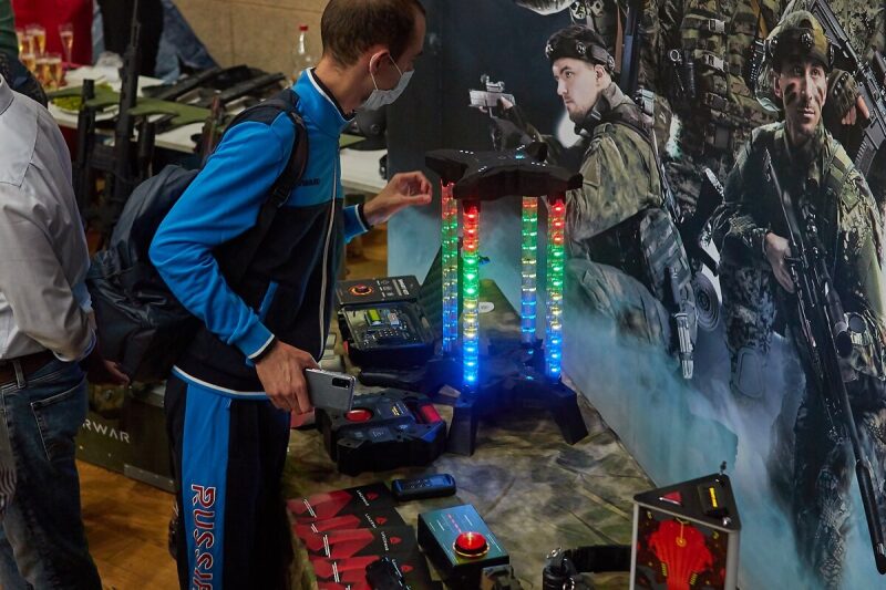 Мужчина в маске изучает светящуюся стойку LASERWAR.
