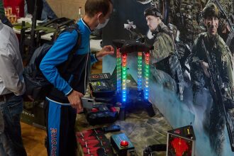 Мужчина в маске изучает светящуюся стойку LASERWAR.