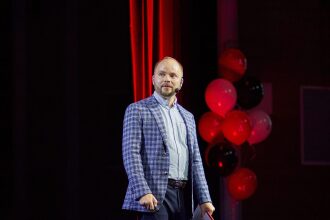 Мужчина в клетчатом пиджаке на фоне красных шаров