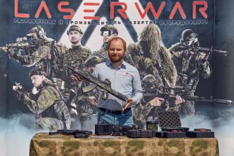 Человек с оружием на фоне бойцов LASERWAR.
