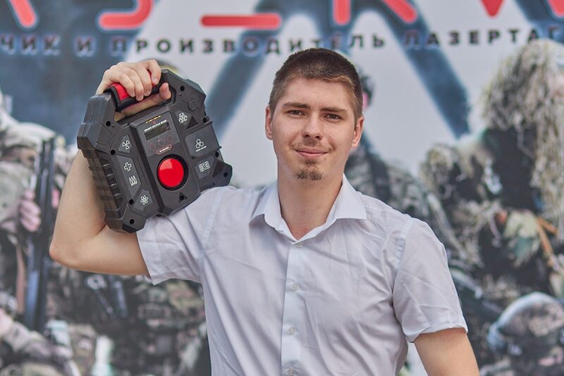 Молодой человек держит игровую базу LASERWAR.