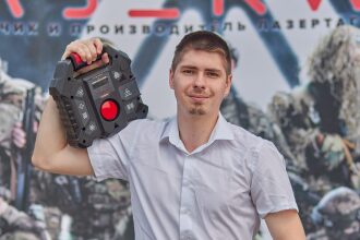 Молодой человек держит игровую базу LASERWAR.