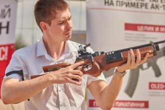 Мужчина демонстрирует лазертаг-винтовку с деревянным прикладом