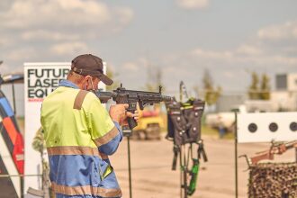 Мужчина в спецодежде целится из черного тагера.