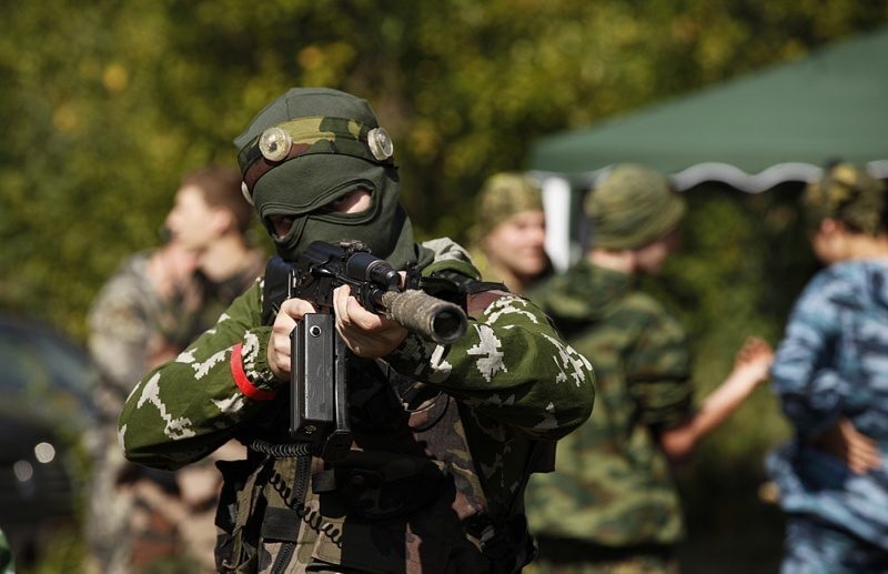 Боец LASERWAR в маске прицеливается из оружия.