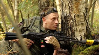 Боец LASERWAR замер у ствола березы