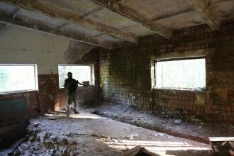 Боец LASERWAR в камуфляже стоит у окна в здании