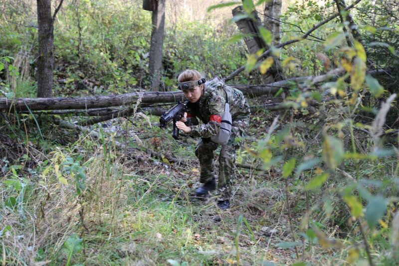 Боец LASERWAR в камуфляже пригнулся у поваленного дерева
