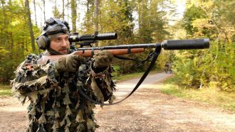 Боец LASERWAR снайперской винтовкой в осеннем лесу
