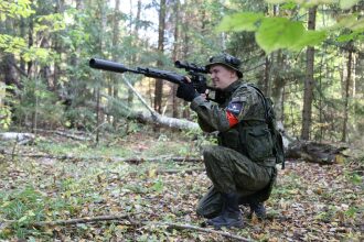 Игрок LASERWAR снайперской винтовкой в осеннем лесу
