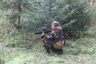 Игрок LASERWAR в камуфляже прицеливается из укрытия.