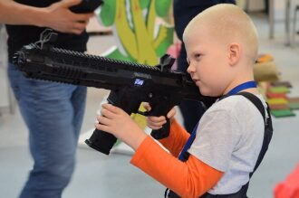 Мальчик с увлечением держит лазертаг-автомат LASERWAR.