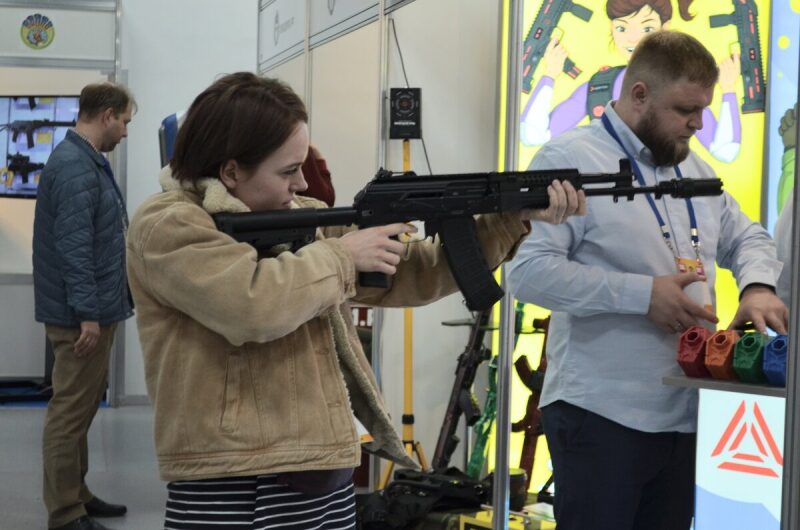 Девушка пробует лазертаг-оружие LASERWAR на выставке.