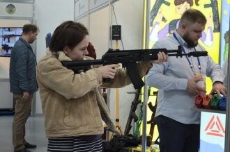 Девушка пробует лазертаг-оружие LASERWAR на выставке.