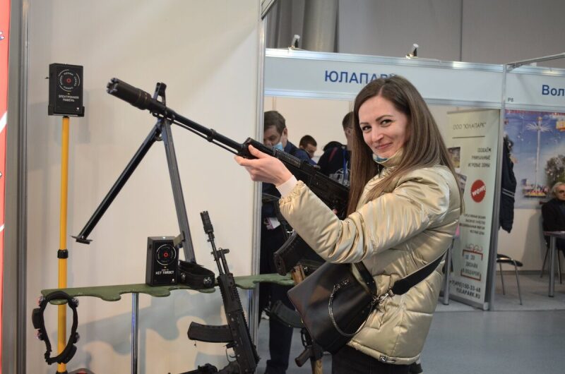Девушка примеряет лазертаг-винтовку LASERWAR на выставке.
