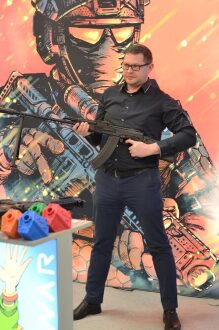 Мужчина держит автомат LASERWAR на фоне комикс-арта.