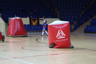 Игрок LASERWAR готовится к выстрелу среди надувных укрытий.