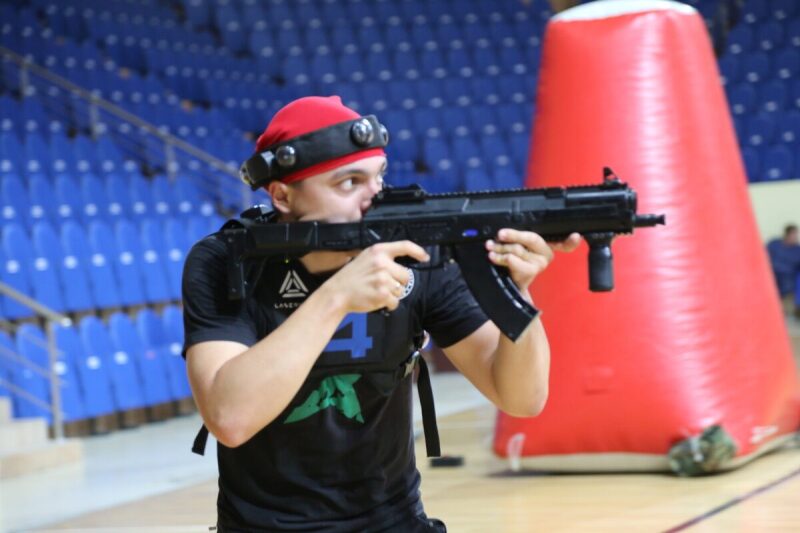 Игрок LASERWAR прицеливается из-за большого красного укрытия.