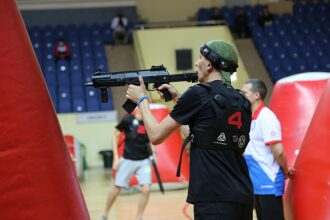 Боец LASERWAR с оружием занимает позицию у укрытия.