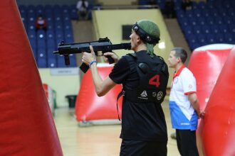 Боец LASERWAR с оружием у красного надувного препятствия.