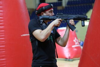 Игрок LASERWAR с оружием занимает позицию у красного укрытия.