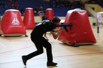 Игрок LASERWAR в движении с оружием у красного укрытия.