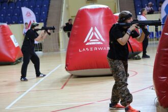 Игрок LASERWAR в камуфляже занимает позицию у красного укрытия.