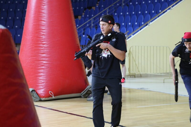 Боец LASERWAR с оружием наготове у красного укрытия.