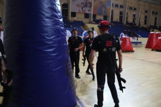 Игроки LASERWAR в черной форме с оружием идут по арене.