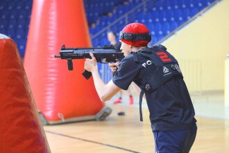 Игрок LASERWAR готовится к стрельбе из-за оранжевого укрытия.