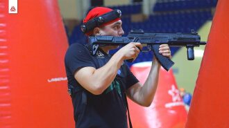Игрок LASERWAR с оружием наводит прицел на противника.
