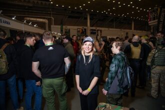 Улыбающаяся женщина в кепке на выставке LASERWAR.