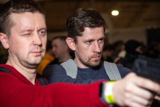 Два игрока LASERWAR готовятся к бою, один прицеливается.